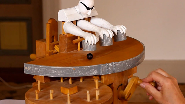 Manually cranked wood toy performs sleight-of-hand magic