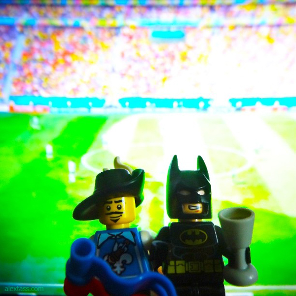 A graphic designer, Alex Tass, is watching the World Cup with his friend, Batman