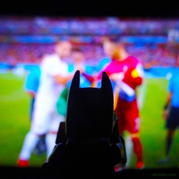 A graphic designer, Alex Tass, is watching the World Cup with his friend, Batman