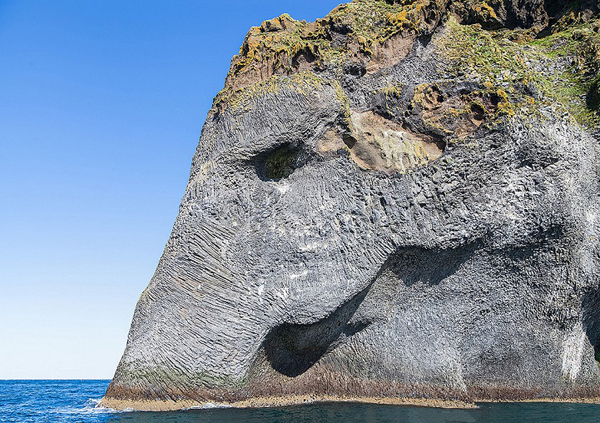 Natural rock formation looks like an elephant drinking from the ocean